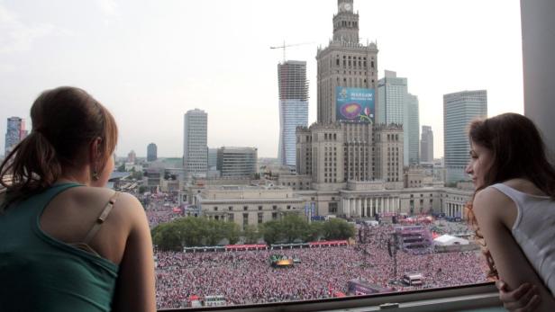Zwei Frauen blicken aus dem Fenster auf eine Menschenmenge in Warschau, Polen.