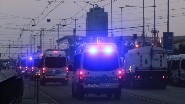 Mehrere Mannschaftswagen der Polizei stehen mit Blaulicht auf einer Straße.