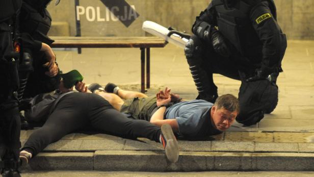 Polizisten nehmen mehrere Personen fest, die auf dem Boden liegen.