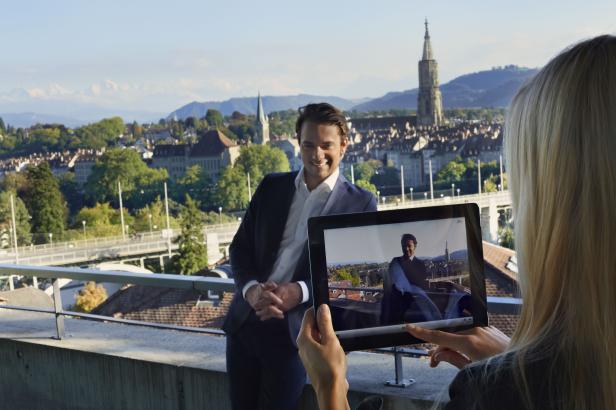 Eine Frau fotografiert einen Mann im Anzug mit Blick auf Bern.