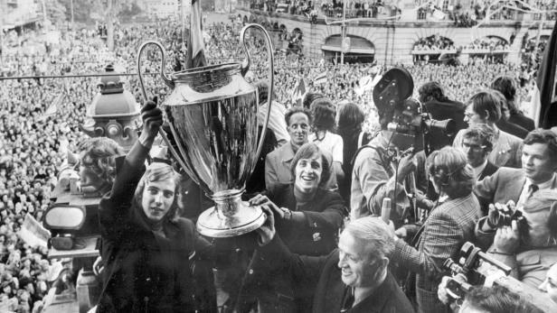 Spieler halten die Trophäe vor einer jubelnden Menschenmenge.