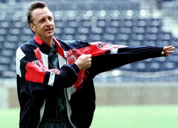 Ein Mann in einer rot-schwarz-weißen Jacke steht auf einem grünen Feld.