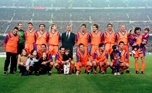 Mannschaftsfoto des FC Barcelona mit Kindern auf dem Rasen vor Zuschauern.