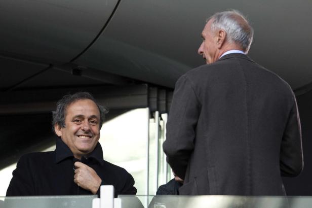 Michel Platini lächelt, während er mit einer anderen Person spricht.