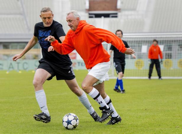Zwei Männer spielen Fußball auf einem grünen Rasenplatz.