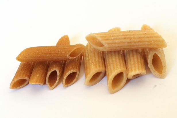 Eine Nahaufnahme von zwei kleinen Häufchen Penne-Nudeln.