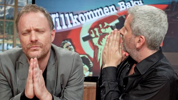 Zwei Männer sitzen vor einem Bildschirm mit der Aufschrift „Willkommen Baku“.