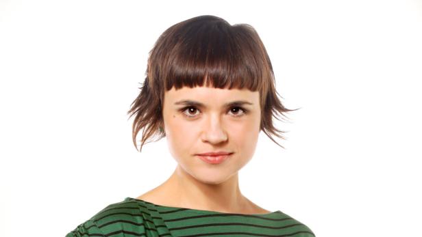 Porträt einer Frau mit braunen Haaren und einem grün gestreiften Oberteil.