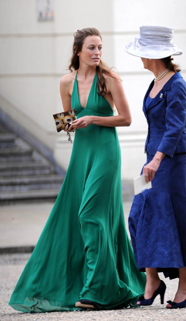 Eine Frau in einem smaragdgrünen Kleid geht mit einer anderen Frau, die einen blauen Anzug trägt.