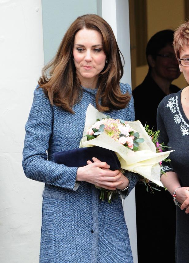 Catherine, Princess of Wales, hält einen Blumenstrauß und eine Clutch in den Händen.