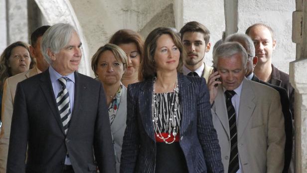 Ségolène Royal Eine Gruppe von formell gekleideten Personen geht durch einen Torbogen.