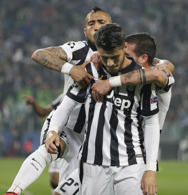 Drei Fußballspieler von Juventus Turin umarmen sich auf dem Spielfeld.