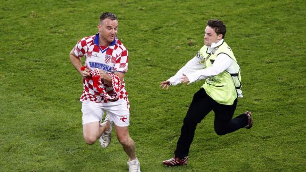 Ein Flitzer im Kroatien-Trikot rennt über einen Rasen, verfolgt von einem Ordner.