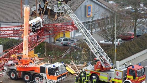 Ein umgestürzter Kran hat ein Aldi-Gebäude beschädigt, Feuerwehrleute sind vor Ort.