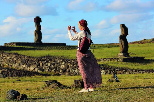 Eine Frau fotografiert die Moai-Statuen auf der Osterinsel.