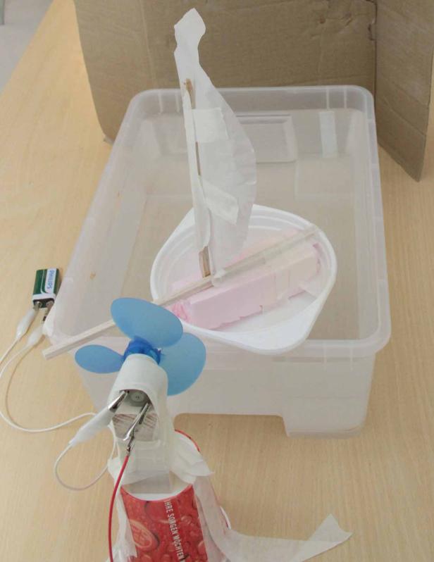 Ein selbstgebautes Spielzeugboot mit Ventilator in einem Wasserbecken.