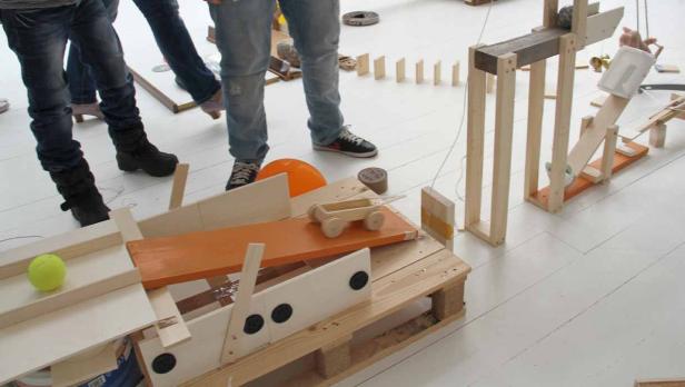 Eine selbstgebaute Murmelbahn aus Holz mit verschiedenen Elementen und Hindernissen.