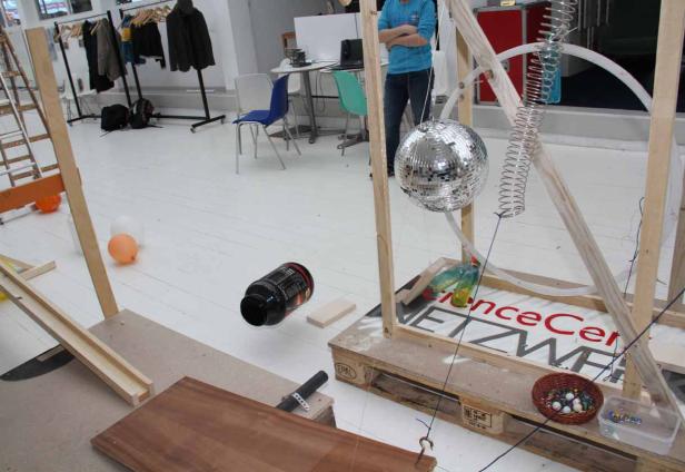 Eine Installation mit einer Discokugel, einer Murmelbahn und anderen Objekten in einem Raum.