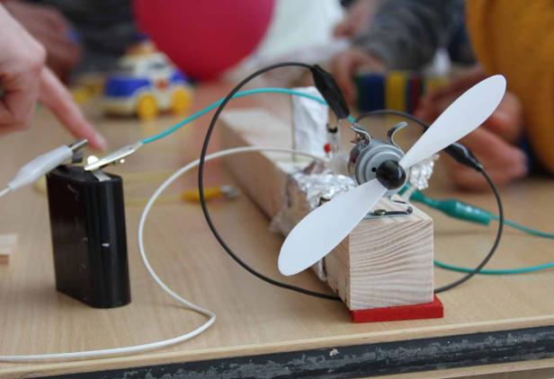 Ein selbstgebauter, batteriebetriebener Mini-Ventilator mit Holzsockel und Propeller.