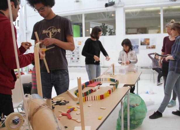 Eine Gruppe von Menschen arbeitet an einem Domino-Projekt in einem hellen Raum.