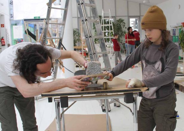 Ein Mann und ein Kind arbeiten gemeinsam an einem Skateboard.
