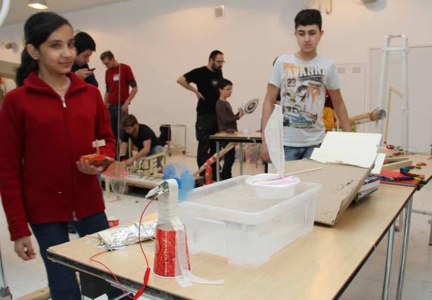 Schüler arbeiten an einem Projekt mit selbstgebauten Booten und Windmaschinen.