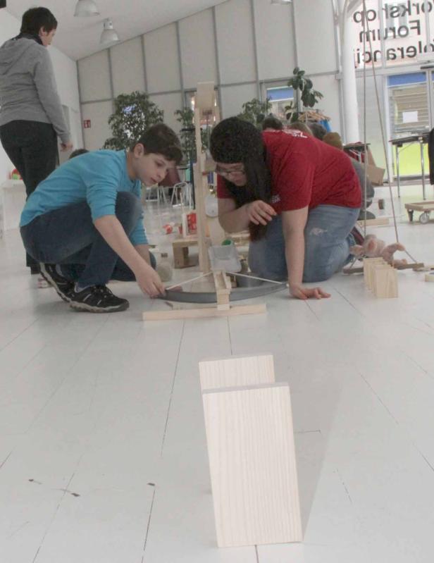 Zwei Kinder bauen gemeinsam an einer Konstruktion aus Holz und anderen Materialien.