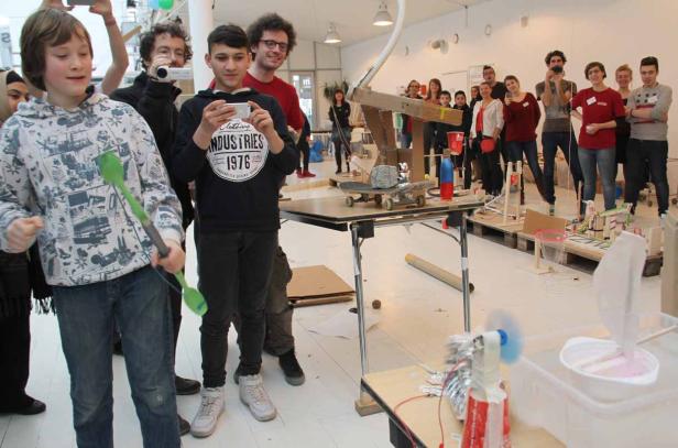 Eine Gruppe von Menschen betrachtet und fotografiert eine Reihe von komplexen Apparaturen.