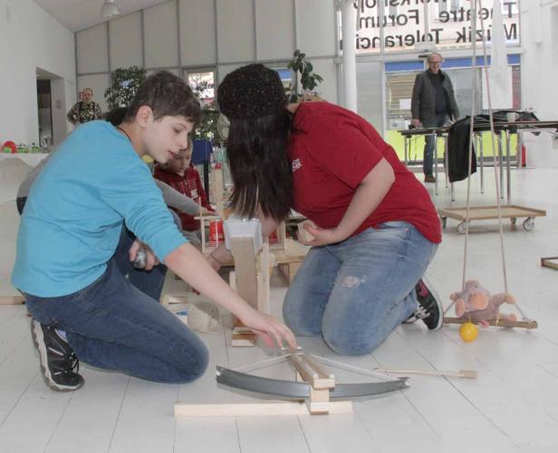 Zwei Jugendliche bauen gemeinsam an einem Projekt mit Holz und anderen Materialien.