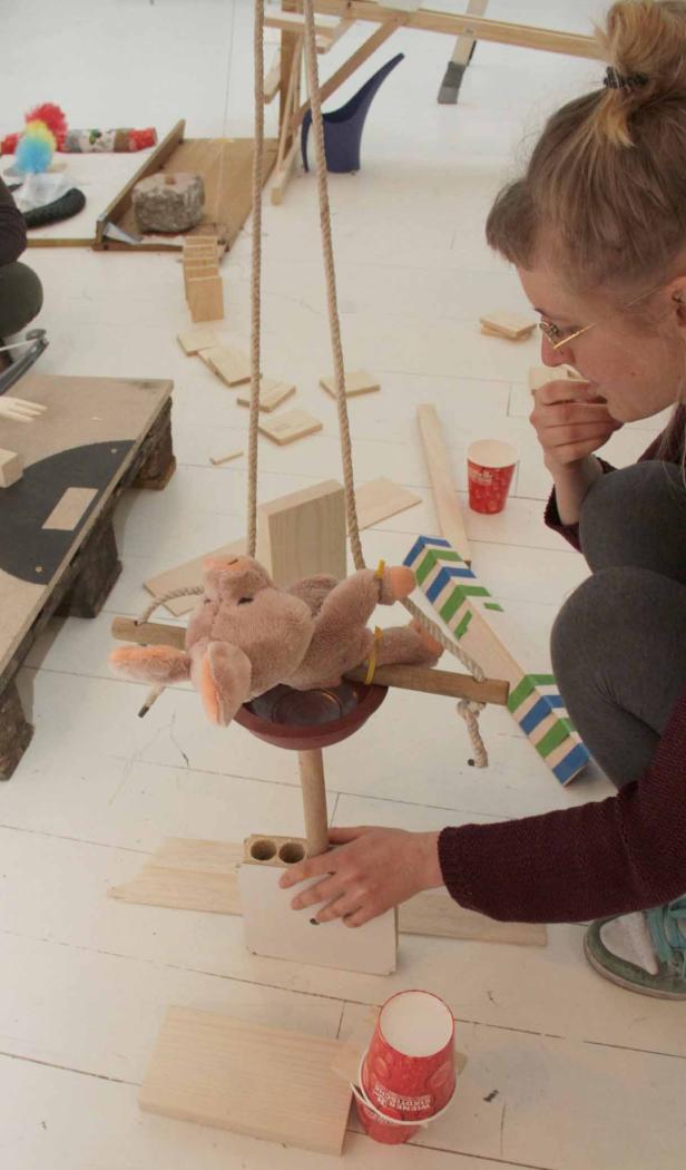 Eine Frau bastelt an einer Schaukel für ein Stofftier-Schwein.