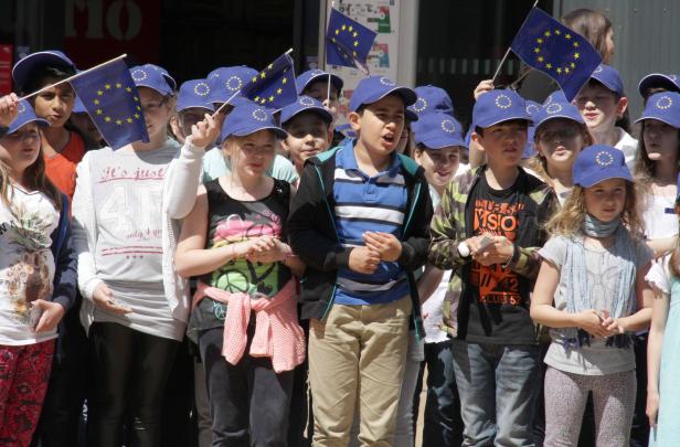 Eine Gruppe von Kindern mit EU-Flaggen und -Kappen demonstriert.