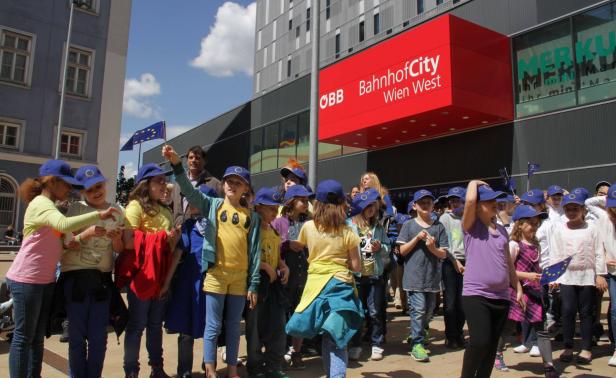 Eine Gruppe Kinder mit EU-Fahnen vor der BahnhofCity Wien West.