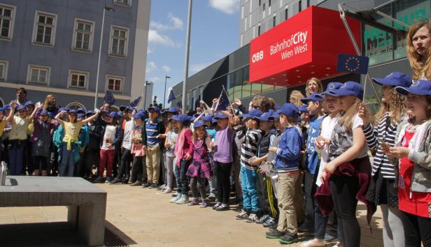 Eine Gruppe Kinder mit EU-Fahnen vor dem BahnhofCity Wien West.