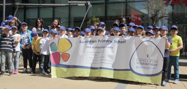 Eine Gruppe von Kindern hält ein Banner der Europäischen Volksschule Goldschlagstraße.