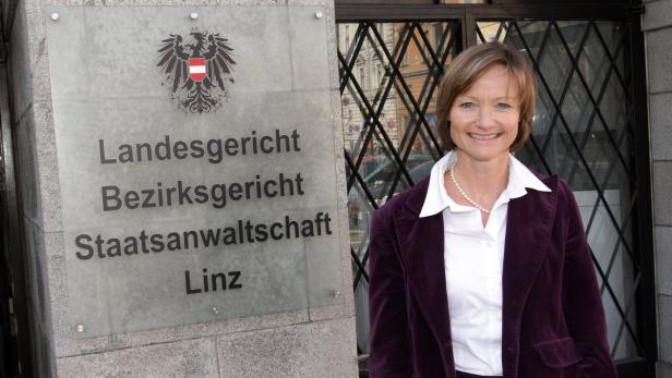 Eine Frau steht vor dem Landesgericht, Bezirksgericht und der Staatsanwaltschaft Linz.