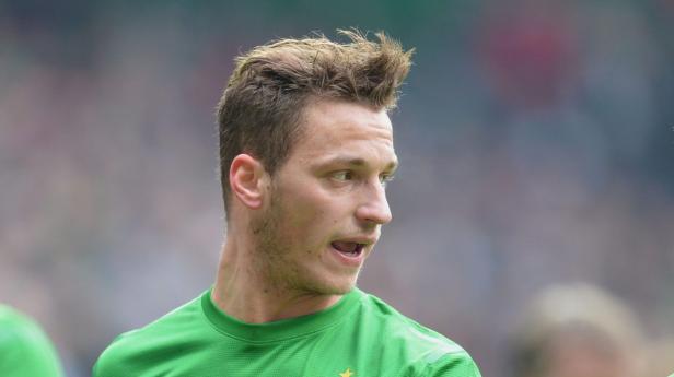 Ein Mann mit blonden Haaren und grünem Trikot schaut zur Seite.
