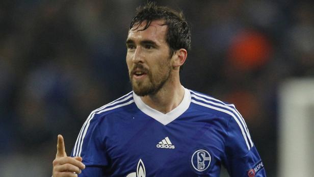 Ein Fußballspieler des FC Schalke 04 in blauem Trikot zeigt mit dem Finger nach oben.