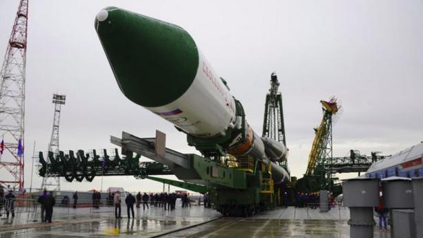 Eine russische Sojus-Rakete steht auf der Startrampe, umgeben von Wartungstürmen und Personal.