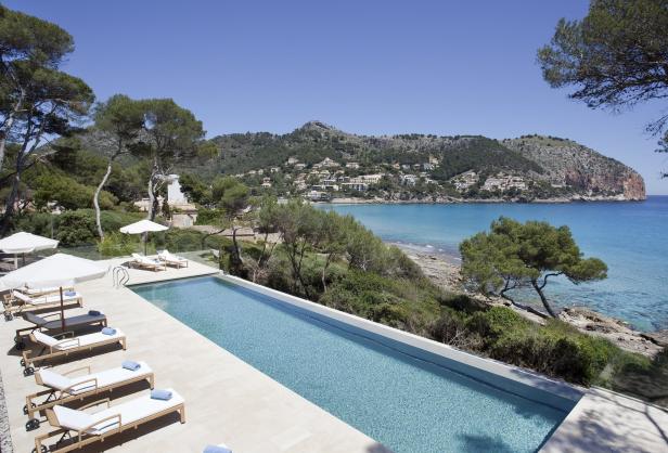 Ein langer Pool mit Liegestühlen blickt auf eine malerische Küstenlandschaft.