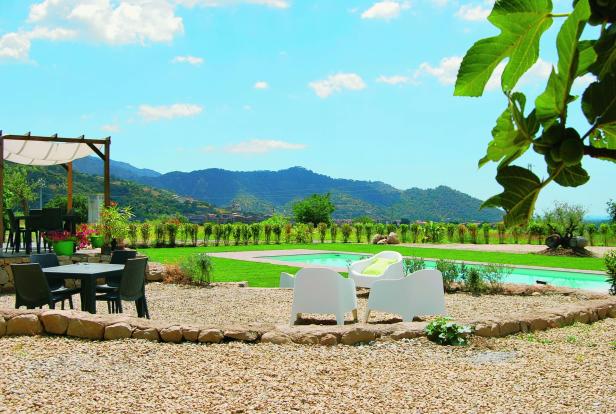 Ein Garten mit Pool, Liegestühlen und Blick auf die Berge.