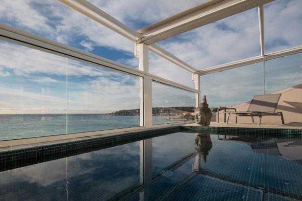 Ein kleiner Pool mit Blick auf das Meer und einer Buddha-Statue am Beckenrand.