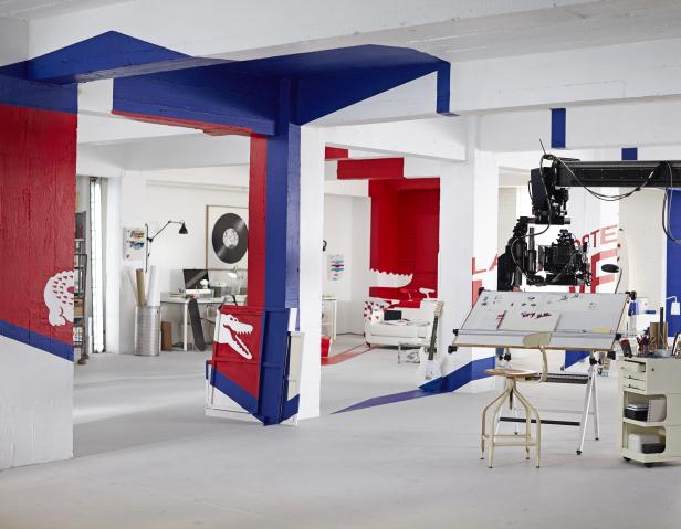 Ein geräumiges Studio mit rot-blau bemalten Säulen und einer Filmkamera auf einem Kran.