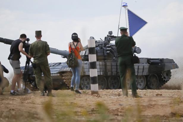 Ein Panzer fährt an Zuschauern und Presse vorbei.