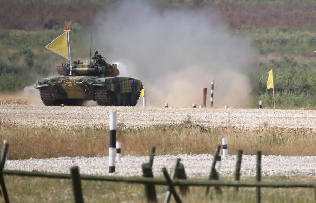 Ein Panzer fährt über ein Übungsgelände und wirbelt Staub auf.