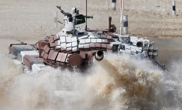 Ein Panzer durchfährt mit hoher Geschwindigkeit eine Wasserfläche.