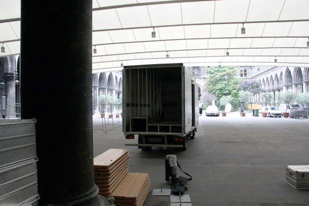 Ein Lieferwagen steht in einem Innenhof mit Arkaden und vorbereitetem Equipment.