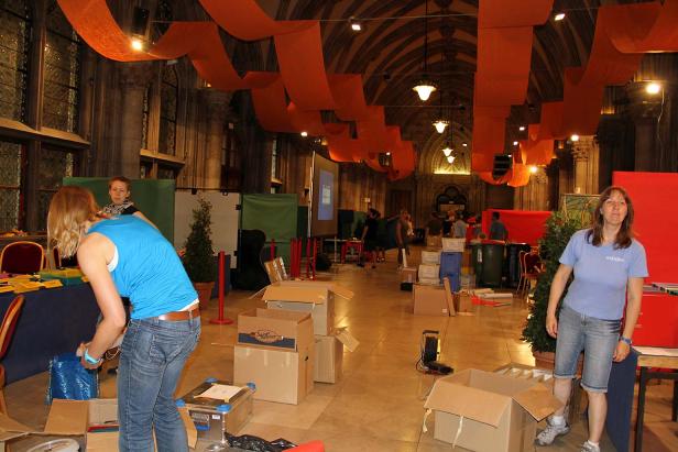 In einem großen Saal bereiten mehrere Personen eine Veranstaltung vor.