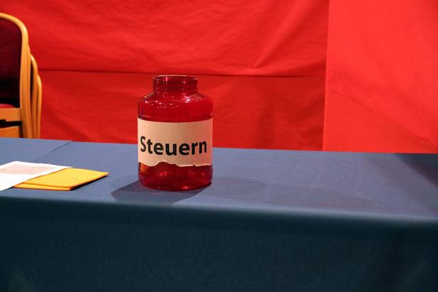 Ein rotes Einmachglas mit der Aufschrift „Steuern“ steht auf einem Tisch.