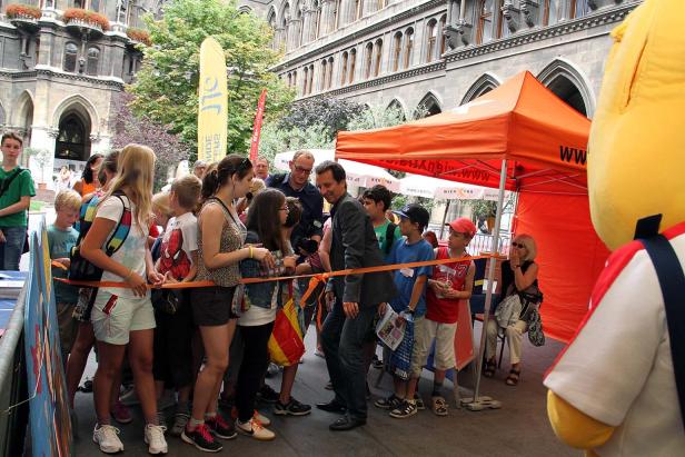 Schaulustige beobachten einen Mann hinter einer Absperrung vor dem Wiener Rathaus.