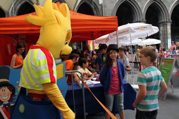 Kinder nehmen an einem Ferienprogramm mit einem gelben Maskottchen teil.